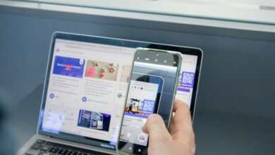 a person holding a cell phone and a laptop