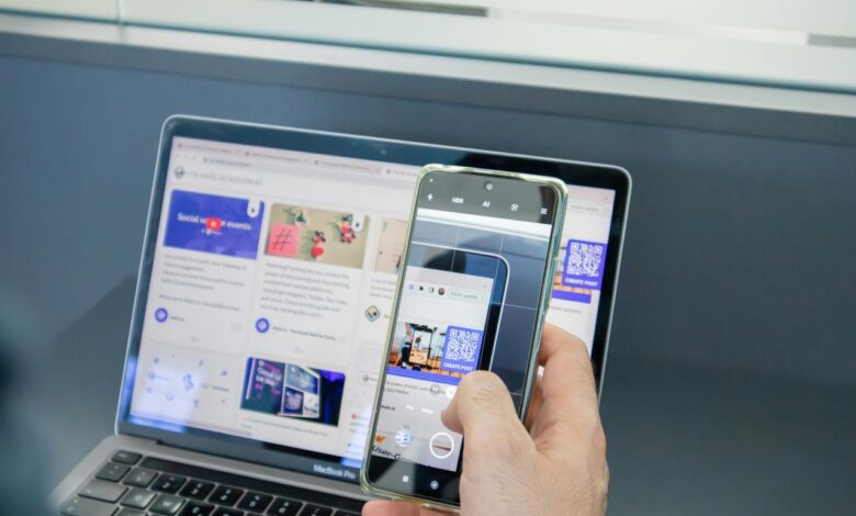 a person holding a cell phone and a laptop