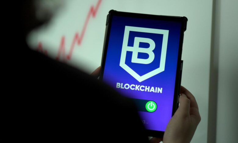 a person holding a cell phone with a blockchain logo on it